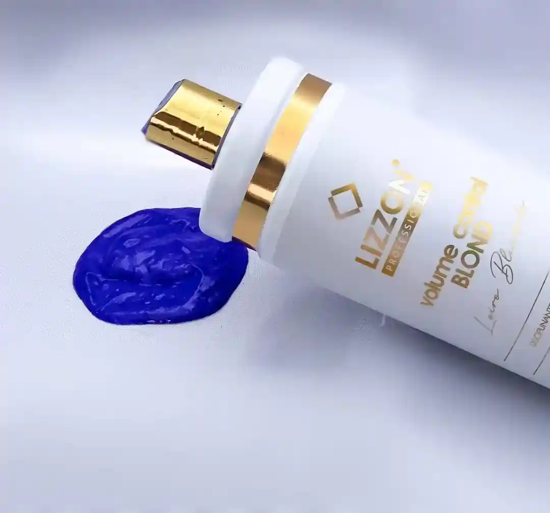 Um frasco branco e dourado de volume control blond (combo3x) repousa ao lado de uma mancha de creme roxo vibrante em uma superfície branca.