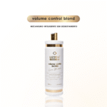 Um frasco branco e dourado com o rótulo Volume Control Blond: Loiro Blindado está na vertical em um fundo branco liso. Acima dele, o texto diz controle de volume blond, progressiva loiro blindado e mecanismo inteligente sem desbotamento.