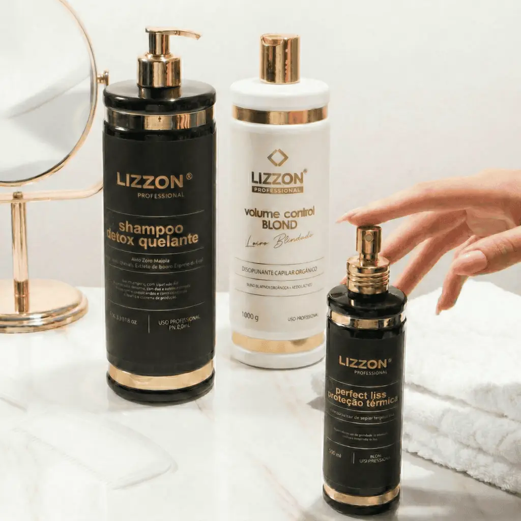 Três produtos de tratamento capilar Kit Liso Blindado Blond estão em uma bancada branca perto de um pequeno espelho redondo, com uma mão alcançando o frasco de spray preto e dourado.