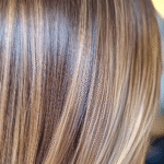 Close-up de cabelos lisos e brilhantes com mechas loiras e castanho-claras, exibindo textura suave, brilho saudável e controle especializado do volume usando o Volume Control Blond (embalagem 2unid black) para obter o visual loiro perfeito.