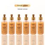 Seis frascos de Finish Glow - 110 ml estão dispostos em uma fileira sobre um fundo branco. Os frascos transparentes têm tampas de spray e rótulos dourados. Acima deles, o texto diz 