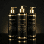 Três garrafas pretas e douradas de 500 ml de 15 em 1 (combo 3 unid 500 ml) estão lado a lado em uma superfície preta reflexiva com dispensadores de bomba, em um fundo escuro.