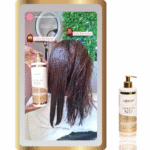 Uma pessoa com cabelos castanhos molhados está sentada em um salão de beleza enquanto uma mão segura um frasco com o rótulo Reversor de Danos - ND próximo ao seu cabelo. Um close-up do frasco do produto aparece no lado direito da imagem.