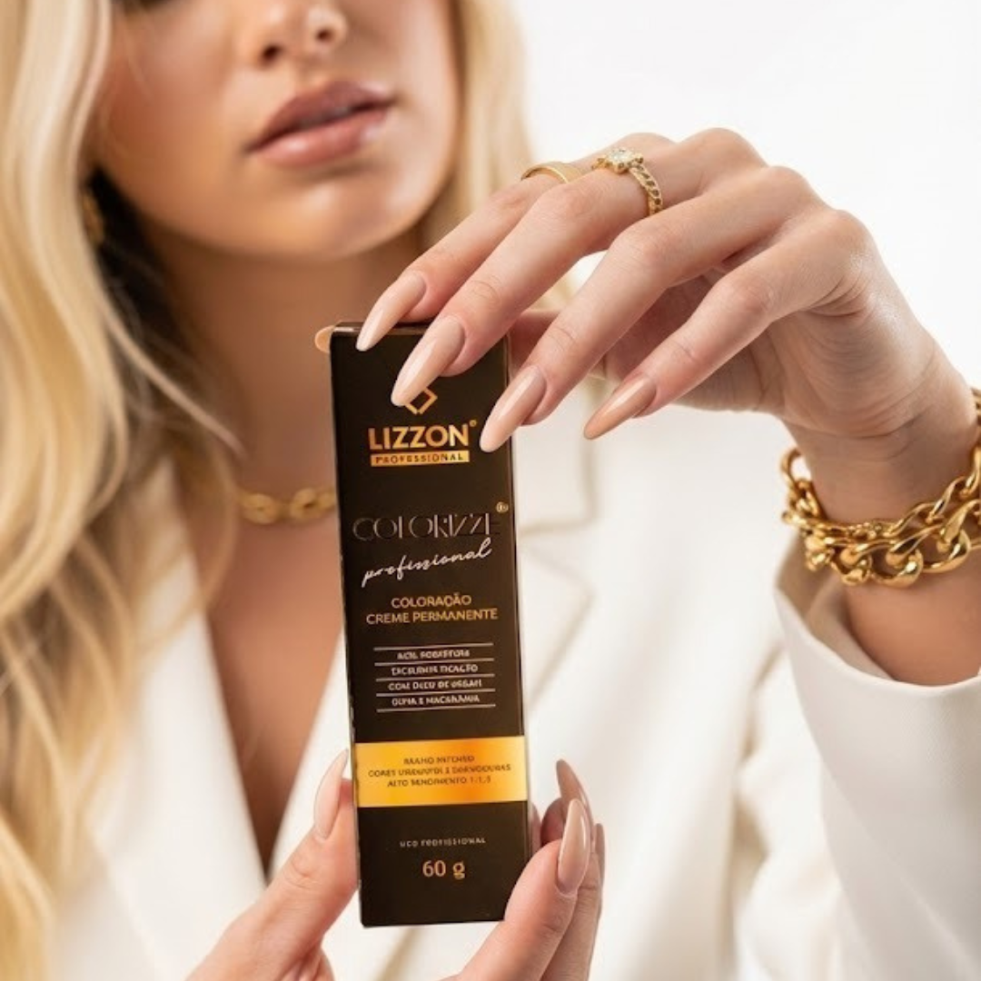 Uma pessoa com unhas longas e bem cuidadas e cabelos loiros segura uma caixa de Colorizze 1.1 Preto azulado. Ela está vestida de branco e usa joias de ouro, incluindo anéis e uma pulseira.