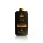 Um frasco preto com uma tampa dourada rotulada Emulsão Oxidante Express 40Vol. 900ml está sobre um fundo branco, contendo 900 ml de líquido.