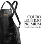 O avental de couro preto com alças ajustáveis e anéis de metal é exibido à esquerda. Um adesivo com o logotipo diz 