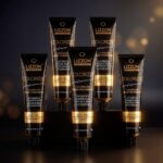 Cinco tubos de Colorizze: Coloração Creme Permanente (combo 5 unidades) com OX Emulsão 20vol 900ml estão dispostos na vertical em uma superfície escura contra um fundo quente e suavemente iluminado.