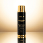 Um frasco preto e dourado de Ativador de Cachos: Creme Leave In Blindagem Capilar, 300 ml, está na vertical em uma superfície reflexiva contra um fundo dourado.