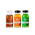 Três frascos de 15 ml do Power Dose Umectação estão expostos lado a lado, contendo líquidos nas cores âmbar, amarelo-alaranjado e verde. Cada frasco possui um rótulo exclusivo em português.