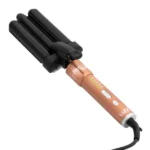 Um MODELADOR BEACH WAVE TRIONDAS BILVOLT, com design de três cilindros nas cores dourado e preto, luzes indicadoras LED e uma alça preta com a marca “LIZZ”, é mostrado conectado à tomada contra um fundo branco.